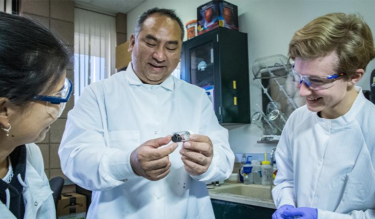 Students and a professor examining an object.